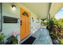 Inviting front porch with a vibrant orange door, colorful brick accents, and lush greenery at 5317 14Th S Ave, Gulfport, FL 33707