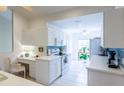 Bright kitchen featuring white cabinets, stainless appliances, blue backsplash, and adjacent desk area at 7137 Cedar Hollow Cir, Bradenton, FL 34203