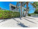Side view of a two-story beach home with a screen porch and white fence at 733 Holly Rd, Anna Maria, FL 34216