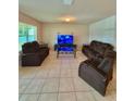 Spacious living room is furnished with reclining sofas, tile floors, and a modern glass coffee table at 1646 Pierpoint St, North Port, FL 34288