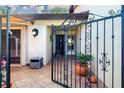 View through the iron gate to a tiled courtyard with potted plants and an outdoor lamp at 3615 Puerta Ct # 8516, Sarasota, FL 34232