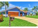 Inviting single-story home boasting a blue exterior, well-manicured lawn, and a wooden garage door at 3636 Torrey Pines Blvd, Sarasota, FL 34238