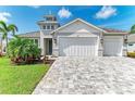 Beautiful home with lush landscaping, a brick driveway, and a three-car garage at 5428 Title Row Dr, Bradenton, FL 34210