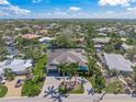 Aerial view of beautiful single-story home with spacious brick driveway, surrounded by lush landscaping and a tranquil canal at 5569 Cape Leyte Dr, Sarasota, FL 34242