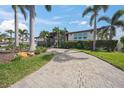 Charming single-story home with lush landscaping, a gray garage door, and a spacious circular brick driveway at 5569 Cape Leyte Dr, Sarasota, FL 34242