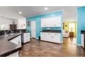 Bright kitchen featuring white cabinets, sleek countertops, wood floors, and a pass-through to the living room at 6710 36 E Ave # 114, Palmetto, FL 34221