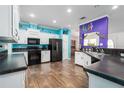 Spacious kitchen with black appliances, white cabinets, tile backsplash, and unique turquoise and purple accents at 6710 36 E Ave # 114, Palmetto, FL 34221
