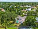 Aerial view of a home with a screened pool nestled in a lush, tree-filled neighborhood with a nearby lake at 8240 Cypress Lake Dr, Sarasota, FL 34243