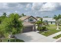 An elevated view of a home with mature trees and landscaping including a three car driveway and stone facade at 9236 Raes Creek Pl, Palmetto, FL 34221