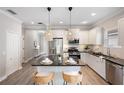 Modern white kitchen featuring an island with bar seating, stainless steel appliances, and stylish pendant lighting at 12261 Stuart Dr, Venice, FL 34293