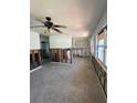 An expansive living room awaits renovation with visible studs and updated ceiling fan at 13434 1St St E, Madeira Beach, FL 33708