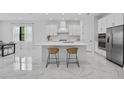 Bright white kitchen featuring an island with bar seating and stainless steel appliances at 13513 Deep Blue Pl, Bradenton, FL 34211