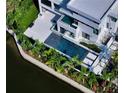 Aerial view showcases a modern home with a large pool, spa, and lush landscaping along the canal at 1610 N Lodge Dr, Sarasota, FL 34239