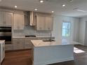 Modern kitchen featuring an island with a marble countertop, stainless steel appliances, and gray cabinets, offering a sleek and functional space at 17134 Savory Mist Cir, Bradenton, FL 34211
