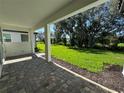 Covered patio with brick pavers overlooks a lush green lawn and mature trees, perfect for outdoor relaxation and entertainment at 17134 Savory Mist Cir, Bradenton, FL 34211