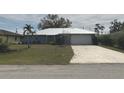 Charming single-story home featuring a lush lawn, a metal roof, and an attached two-car garage at 22321 Yonkers Ave, Port Charlotte, FL 33952