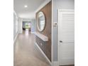 Modern entryway with a wood accent wall, a round mirror, and neutral-toned tile flooring at 3355 Hilltop Cir, Bradenton, FL 34211