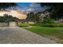 Lovely home with a brick driveway and beautiful landscaping under a colorful sunset sky at 5415 13Th Avenue W Dr, Bradenton, FL 34209
