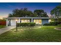 Dusk view of a single-story home features a well-manicured lawn, and a sunny yellow front door at 5685 36Th N Ave, St Petersburg, FL 33710