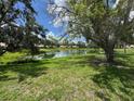 Relaxing backyard featuring a pond, lush green grass, and mature trees under a partly cloudy sky at 5803 Garden Lakes Palm, Bradenton, FL 34203