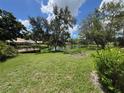 Scenic backyard featuring a pond, a wooden dock, lush green grass, and mature trees under a partly cloudy sky at 5803 Garden Lakes Palm, Bradenton, FL 34203