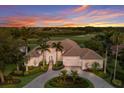 Beautiful home at sunset with mature palms, manicured landscaping, and a serene golf course view at 7144 Ashland Gln, Lakewood Ranch, FL 34202
