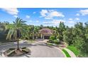 Residential home on a private lot with a circular driveway, mature trees, and lush landscaping at 7628 Haddington Cv, Lakewood Ranch, FL 34202
