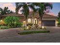 Charming single-Gathering home featuring a tile roof, paved driveway, and lush tropical landscaping at 7628 Haddington Cv, Lakewood Ranch, FL 34202