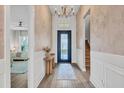 Elegant foyer features a decorative table, rug, chandelier, stylish door and hardwood floors at 8209 Redonda Loop, Lakewood Ranch, FL 34202