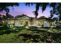 Charming one-story home featuring a well-manicured lawn, and a welcoming front porch at dusk at 13640 2Nd E Ave, Bradenton, FL 34212