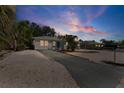 Quaint one-story home with a driveway and rock landscaping, complimented by lush, mature trees at sunset at 1404 Dartmouth Dr, Bradenton, FL 34207