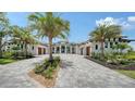 Beautiful home exterior with a large driveway, mature palm trees, and three-car garages on either side of the entryway at 15315 Anchorage Pl, Lakewood Ranch, FL 34202