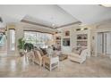 Elegant living room featuring neutral tones, tiled floors, a tray ceiling, and expansive backyard views at 2016 White Feather Ln, Nokomis, FL 34275