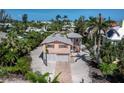 Coastal home featuring a two-car garage, shell driveway, lush landscaping, and a charming exterior design at 663 Penfield St, Longboat Key, FL 34228