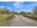Estate home featuring stone wall details and a long driveway, surrounded by lush landscaping at 6633 Old Ranch Rd, Sarasota, FL 34241
