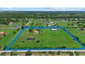Aerial view of a sprawling estate featuring a home, pond, outbuilding, and lush green pastures at 6805 225Th E St, Bradenton, FL 34211