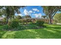 Beautifully landscaped front yard of tan single-story home with mature trees, lush lawn and manicured flower beds at 7426 Weeping Willow Blvd, Sarasota, FL 34241