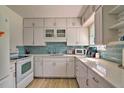 Bright kitchen with modern white cabinets, stainless steel appliances, and elegant backsplash, perfect for cooking at 7511 1St W Ave, Bradenton, FL 34209