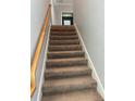 Carpeted staircase with wooden handrail leading to the upper level of the home at 10054 Crooked Creek Dr # 201, Venice, FL 34293