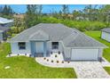 An elevated view of a single Gathering home displaying an attached two car garage and manicured landscaping at 10443 Riverside Rd, Port Charlotte, FL 33981