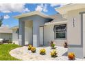 Inviting home entrance with decorative stone landscaping, colorful foliage and grey toned exterior at 10443 Riverside Rd, Port Charlotte, FL 33981
