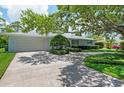 Well-kept single-story home showcasing a green lawn and mature shade trees over a driveway at 1541 Flower Dr, Sarasota, FL 34239