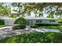 Attractive single-story home with a manicured lawn and shrubbery leading to a light-colored exterior at 1541 Flower Dr, Sarasota, FL 34239