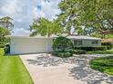 Single-story home featuring a pristine front lawn, driveway and mature landscaping at 1541 Flower Dr, Sarasota, FL 34239