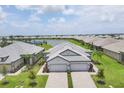 Aerial view of neighborhood, showcasing the home's tile roof, two-car garage and nearby lake at 17823 Cherished Loop, Bradenton, FL 34211