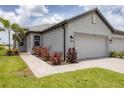 Side view of a light gray home showcasing a two-car garage, paved walkway and colorful landscaping at 17823 Cherished Loop, Bradenton, FL 34211