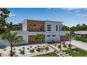 Contemporary white and wood home with tidy landscaping, paved walkway, and manicured lawn at 2124 Clematis Pl, Sarasota, FL 34239