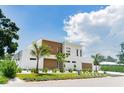 Modern two-story home featuring a flat roof, wood accents, and a manicured front yard with tropical landscaping at 2124 Clematis Pl, Sarasota, FL 34239