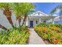 Inviting front entrance with a tiled walkway, vibrant flower bushes and mature palm trees at 4714 Seneca Park Trl, Bradenton, FL 34211