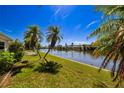 Backyard featuring lush green lawn, mature palm trees, and serene waterfront views at 564 Spanish N Dr, Longboat Key, FL 34228